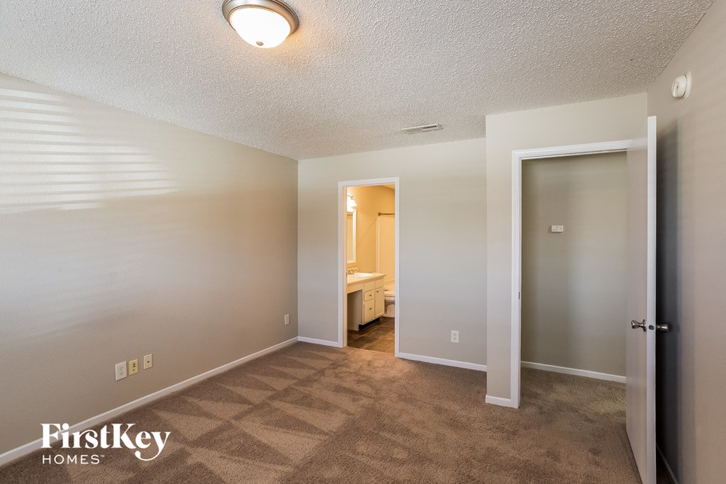 A carpeted room with a doorway leading to another room.
