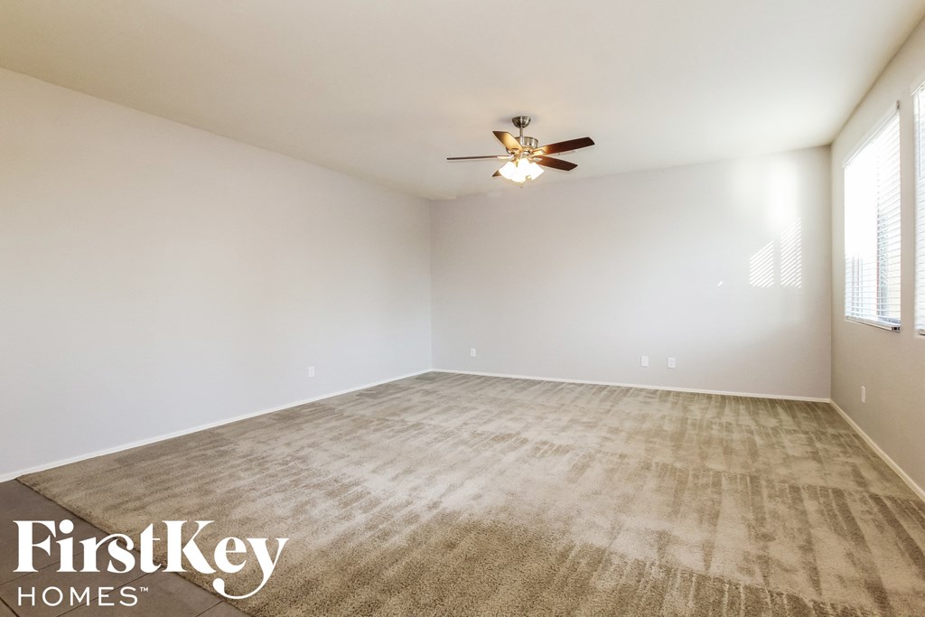 the spacious living room with carpeting and a ceiling fan
