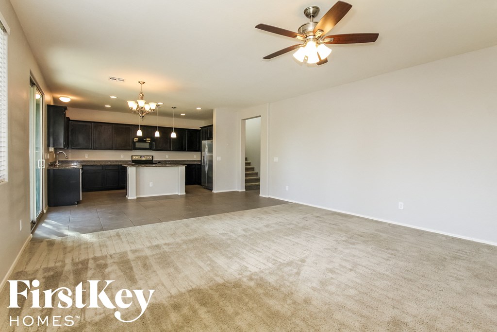 an empty living room and kitchen with a ceiling fan