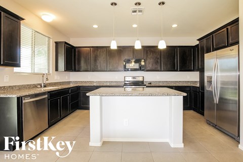 a kitchen with black cabinets and granite counter tops and stainless steel appliances