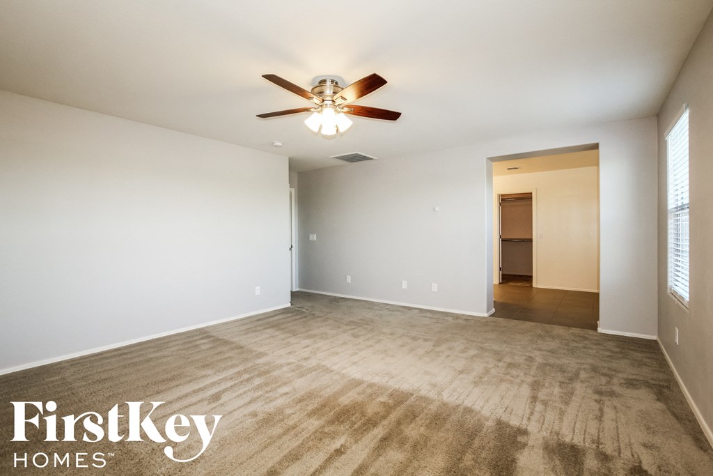 an empty living room with white walls and a ceiling fan