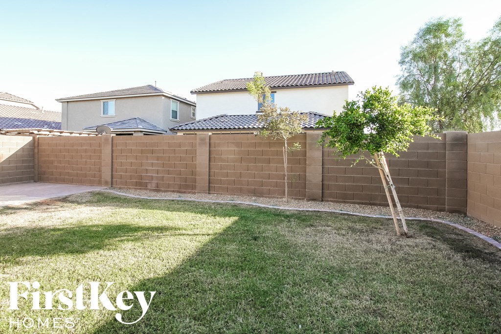 the backyard of a house with a fence and a tree