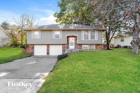 a gray house with white garage doors and a green lawn