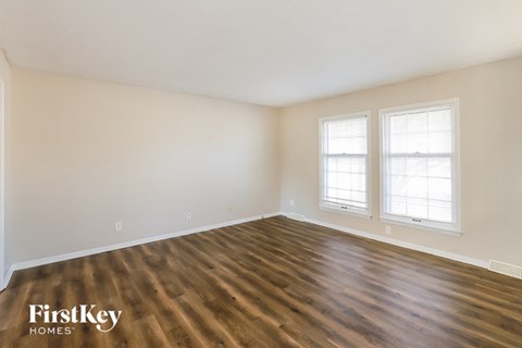 the living room of a home with wood flooring and two windows