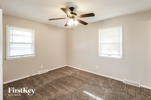 a bedroom with a ceiling fan and two windows