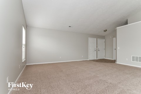 a spacious living room with beige carpet and white doors