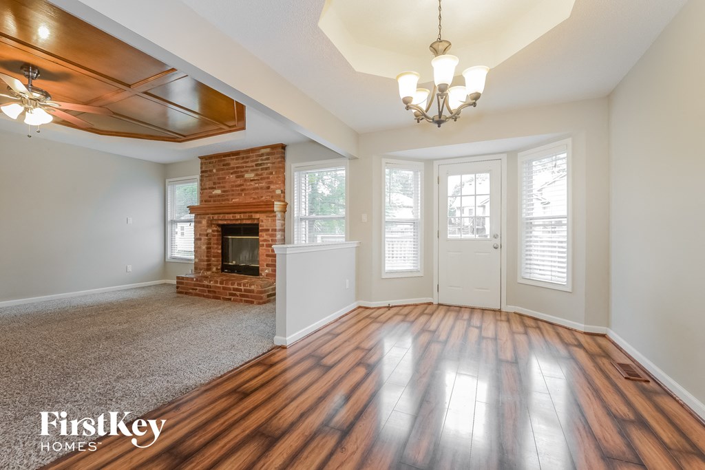 an empty living room with a brick fireplace and wooden floors