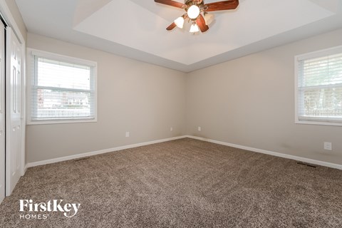 the living room of a home with carpet and a ceiling fan