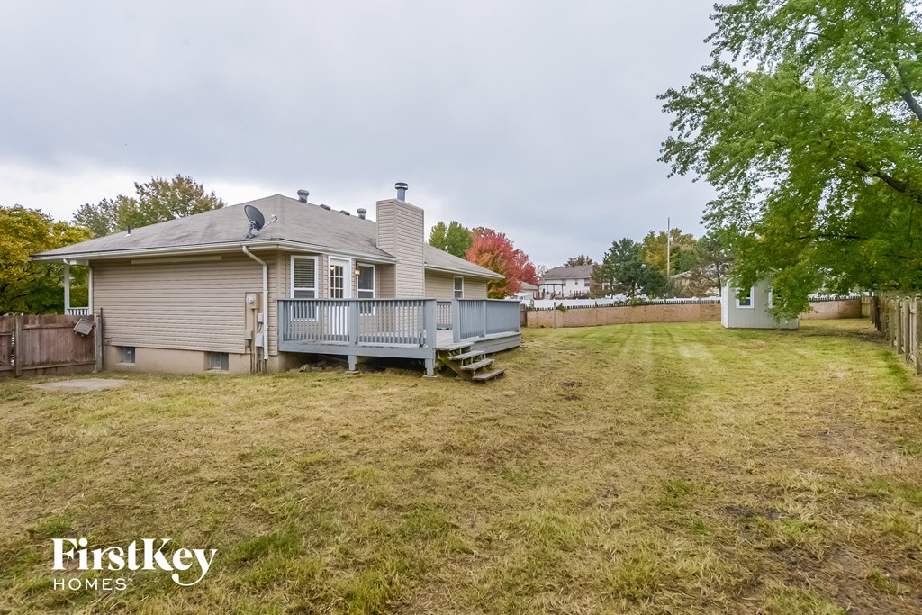 the backyard of a house with a deck and a fence