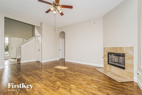 A spacious living room with a fireplace and a ceiling fan.