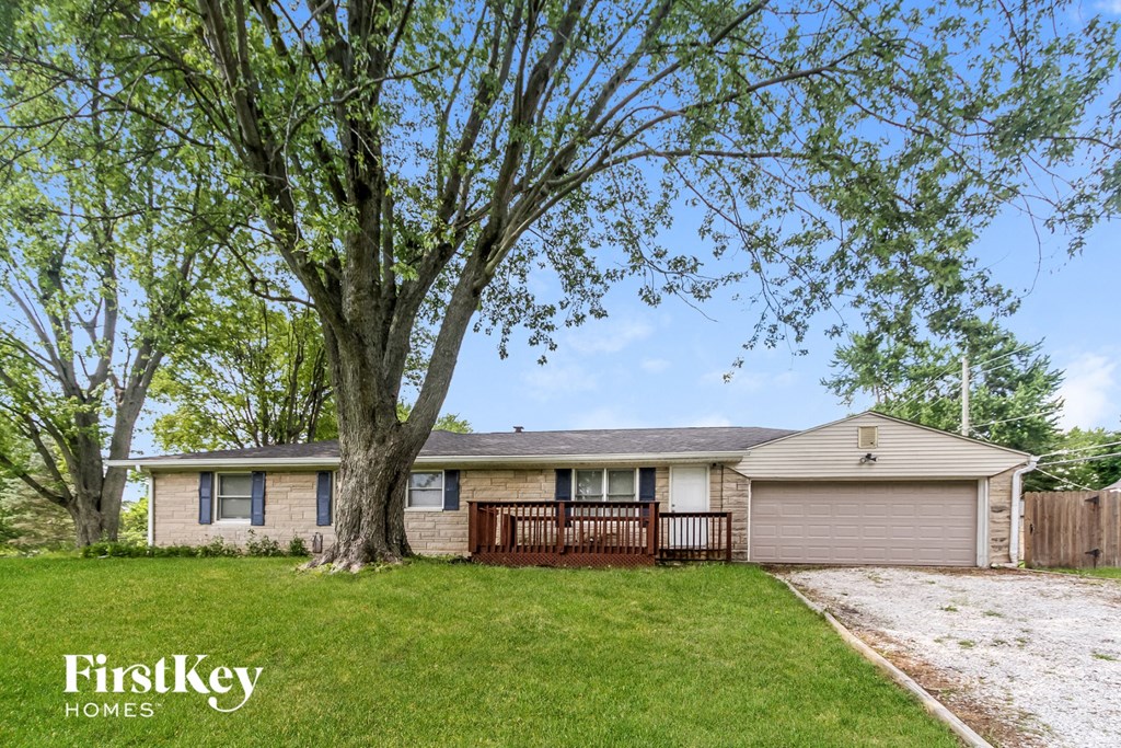 a home with a large tree in the yard and a wooden fence