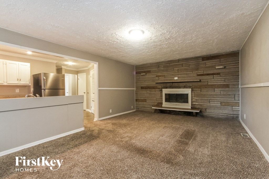 a living room with a brick fireplace and a kitchen