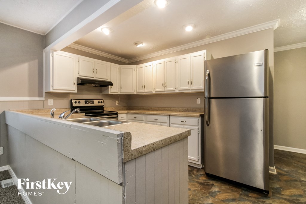 a kitchen with white cabinets and a stainless steel refrigerator