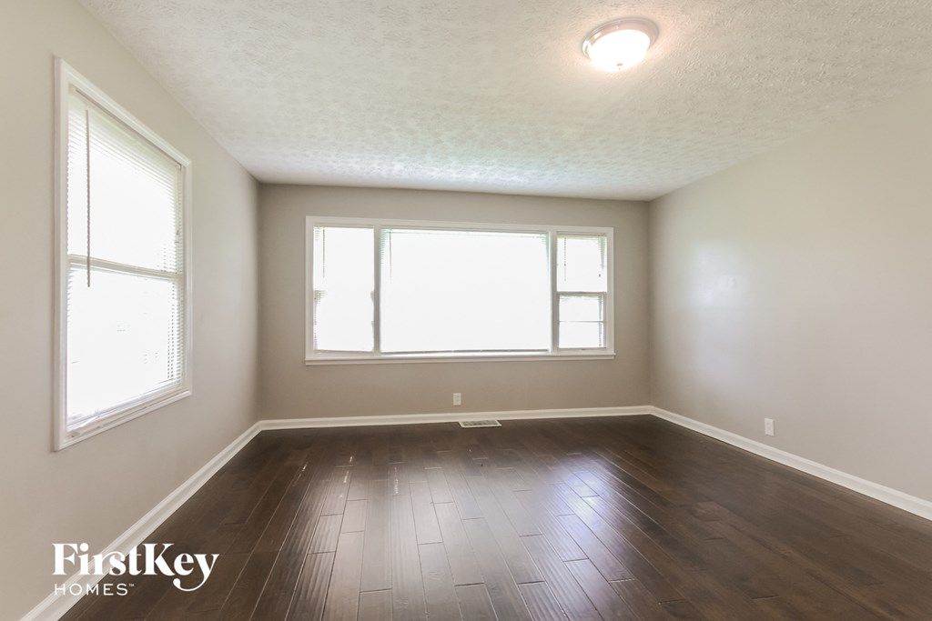 an empty living room with wood floors and a window