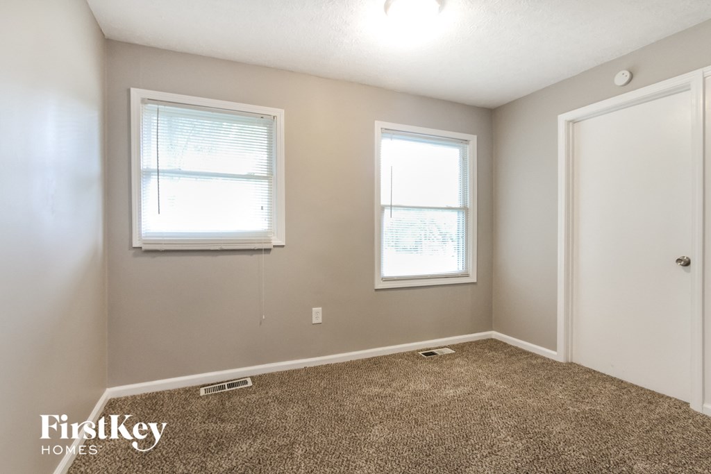 a bedroom with a carpeted floor and two windows