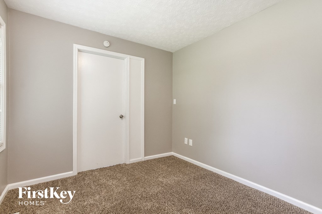 a bedroom with carpet and a door to a closet