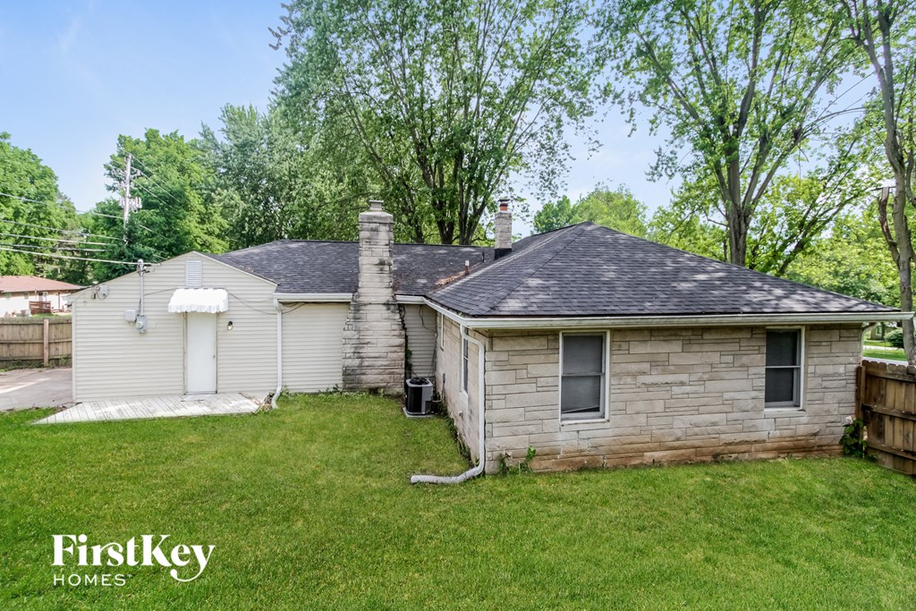 a small white brick house with a yard and a tree