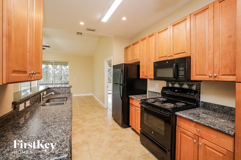 A kitchen with wooden cabinets and black appliances.