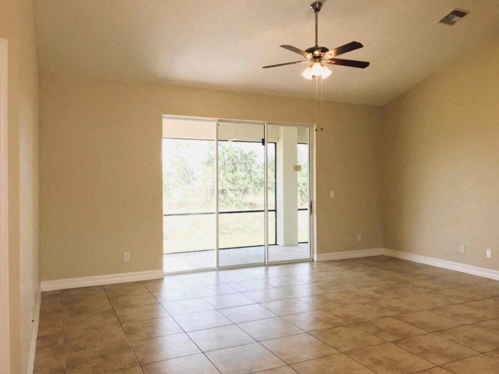 A room with a ceiling fan and sliding glass doors.