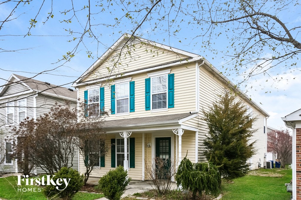 A white house with a green trim and a sign that says "FirstKey Homes".