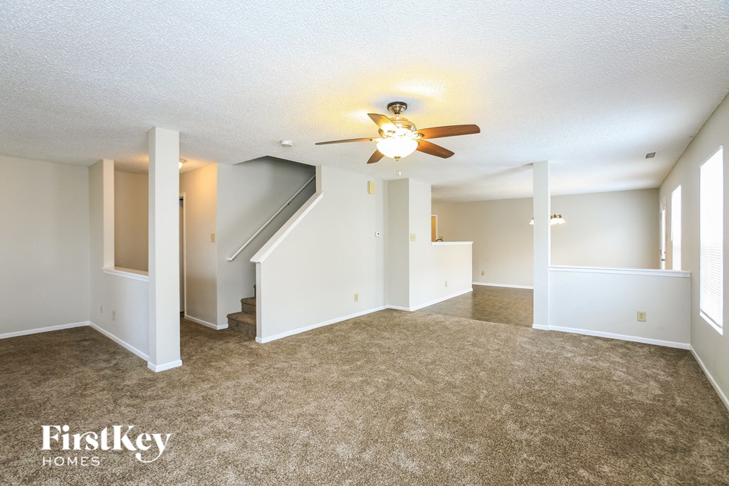 A spacious room with a carpeted floor and a ceiling fan.