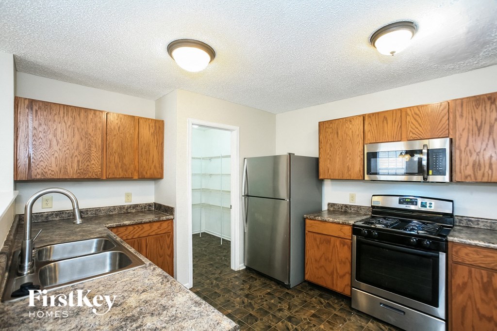 A kitchen with wooden cabinets and a stainless steel refrigerator.