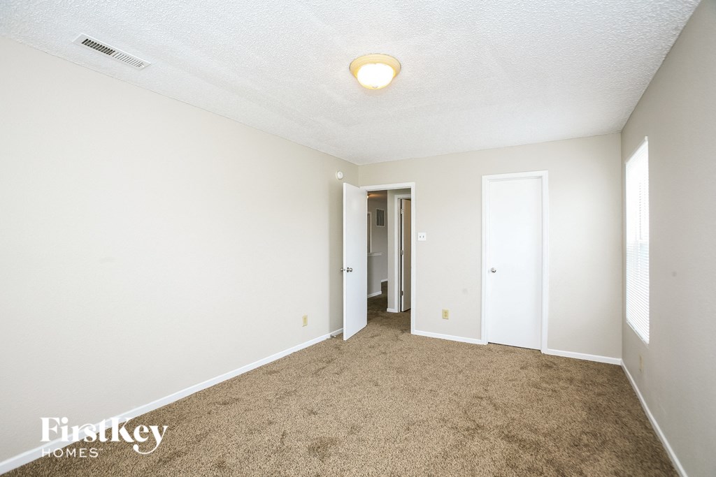 A room with a carpeted floor and a doorway leading to another room.