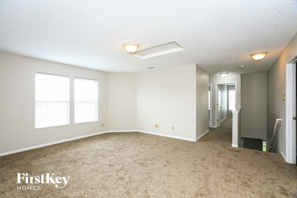 A spacious room with a carpeted floor and a doorway leading to another room.