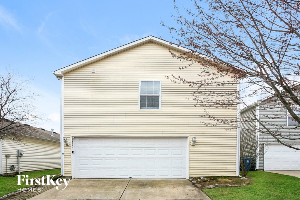 A beige house with a white garage door and a window.