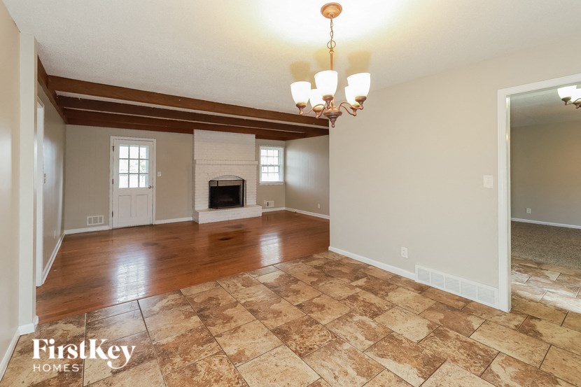 A large empty room with a fireplace and a chandelier.