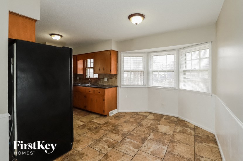 A black fridge is in a kitchen with brown tile flooring.