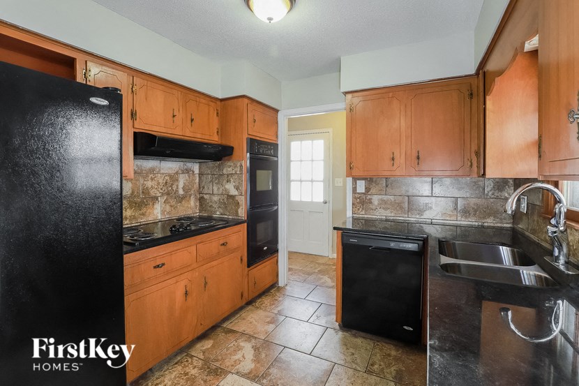 A kitchen with a black fridge and wooden cabinets.