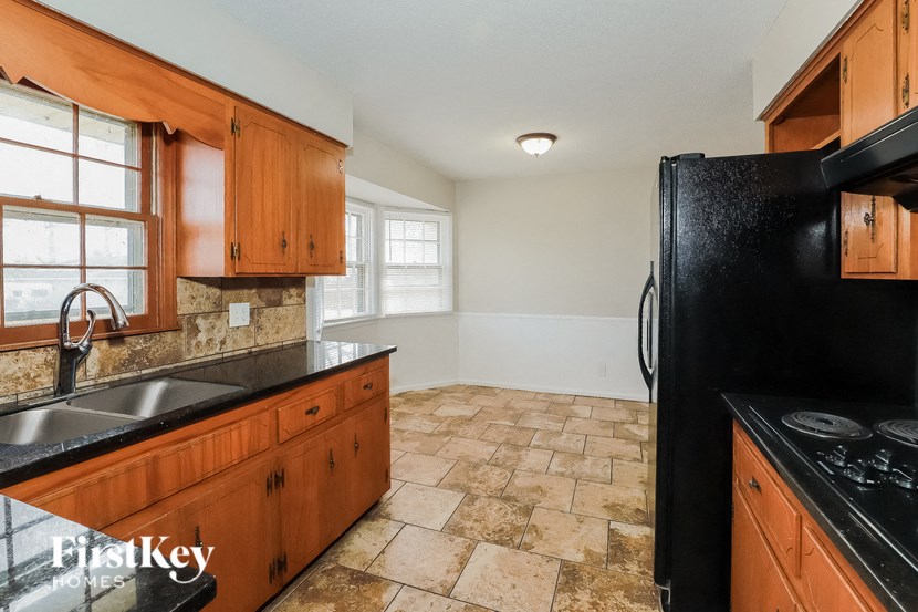 A kitchen with wooden cabinets and a black refrigerator.