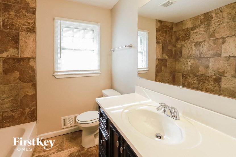 A bathroom with a toilet, sink, and tiled walls.
