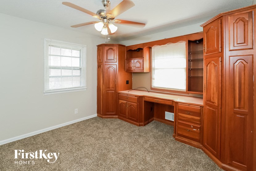 A room with a desk and a fan.