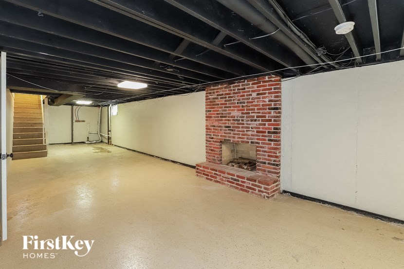 A large empty room with a fireplace and a staircase.