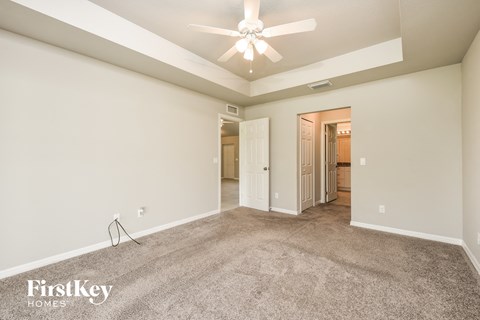 a spacious living room with carpet and a ceiling fan