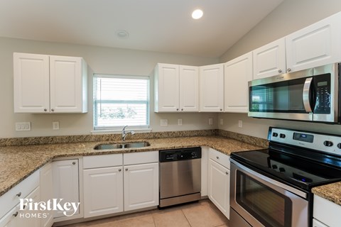 A kitchen with white cabinets and a black stove top oven.