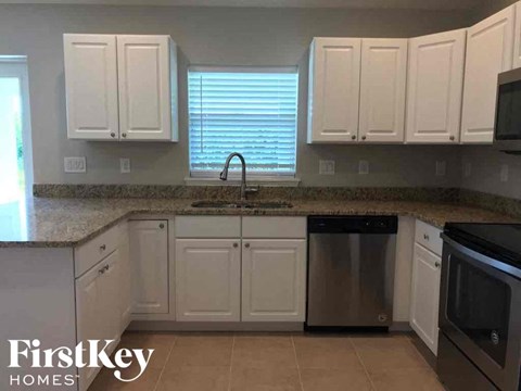 A kitchen with white cabinets and a granite countertop.