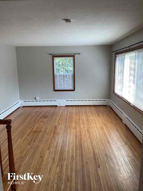 an empty living room with wood floors and a window