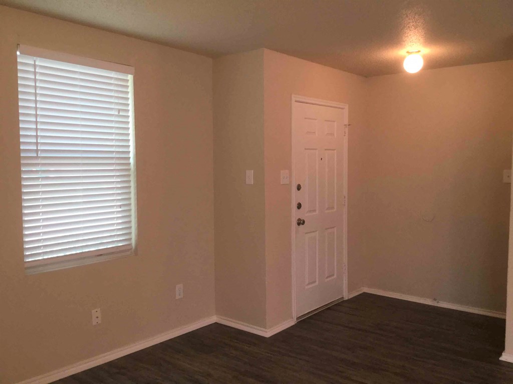an empty room with a white door and a window