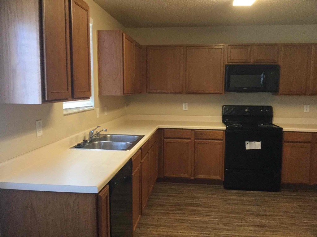 an empty kitchen with wooden cabinets and a sink