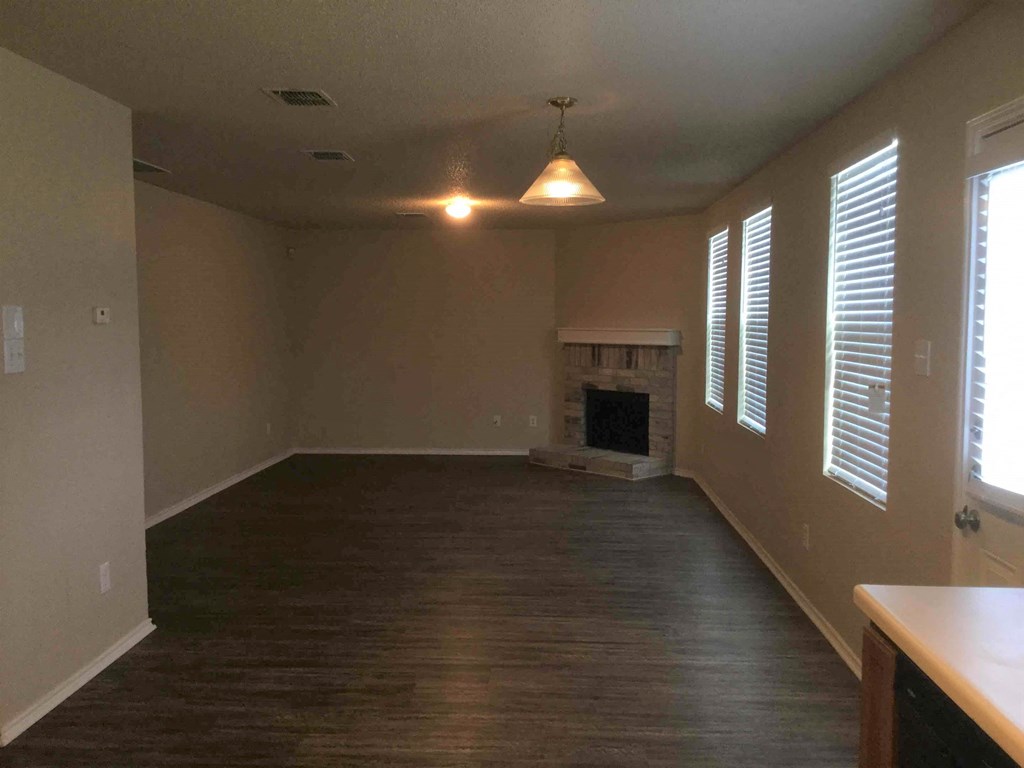 an empty living room with wood floors and a fireplace
