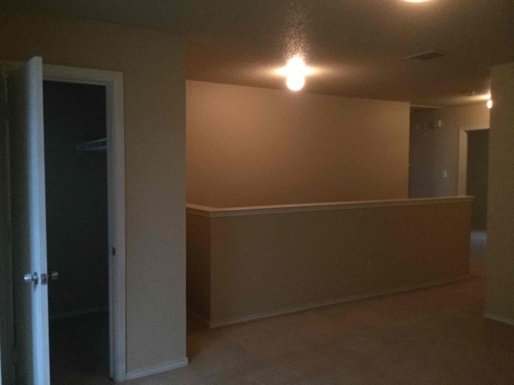 an empty living room with the door open to a hallway