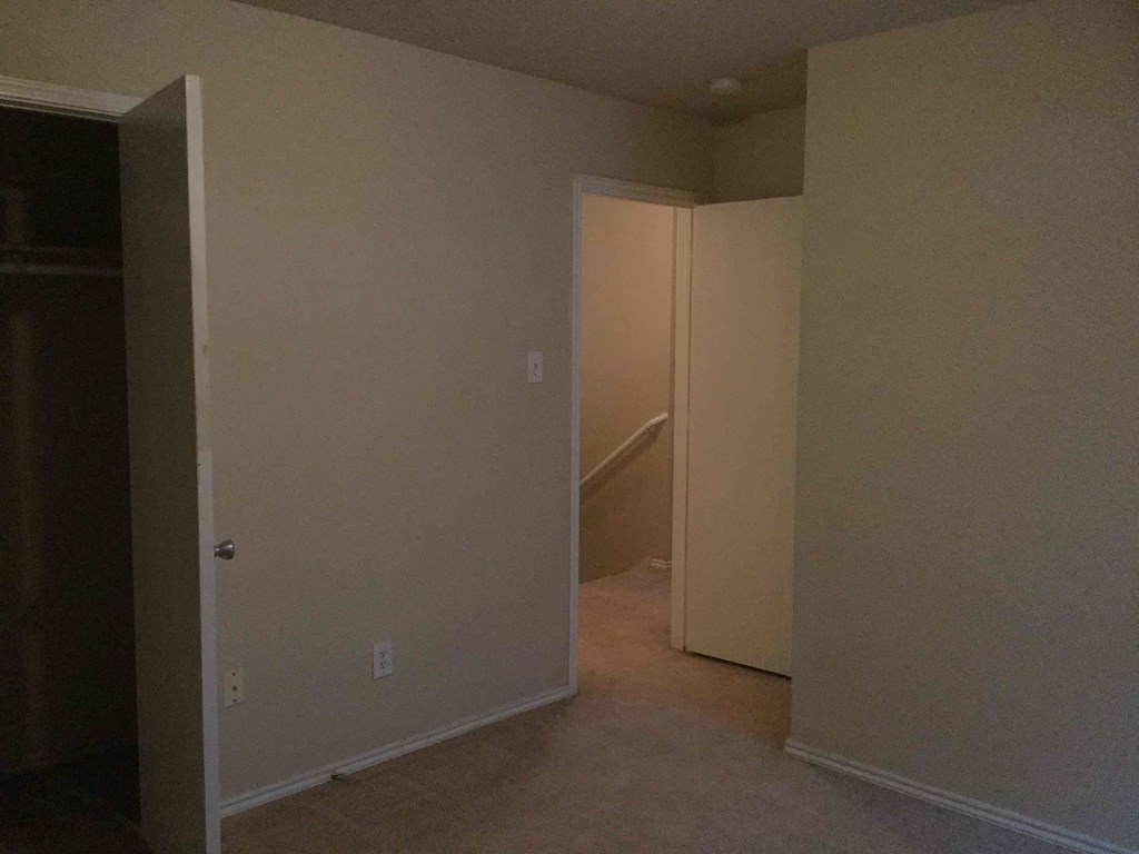 an empty room with an open door and a staircase