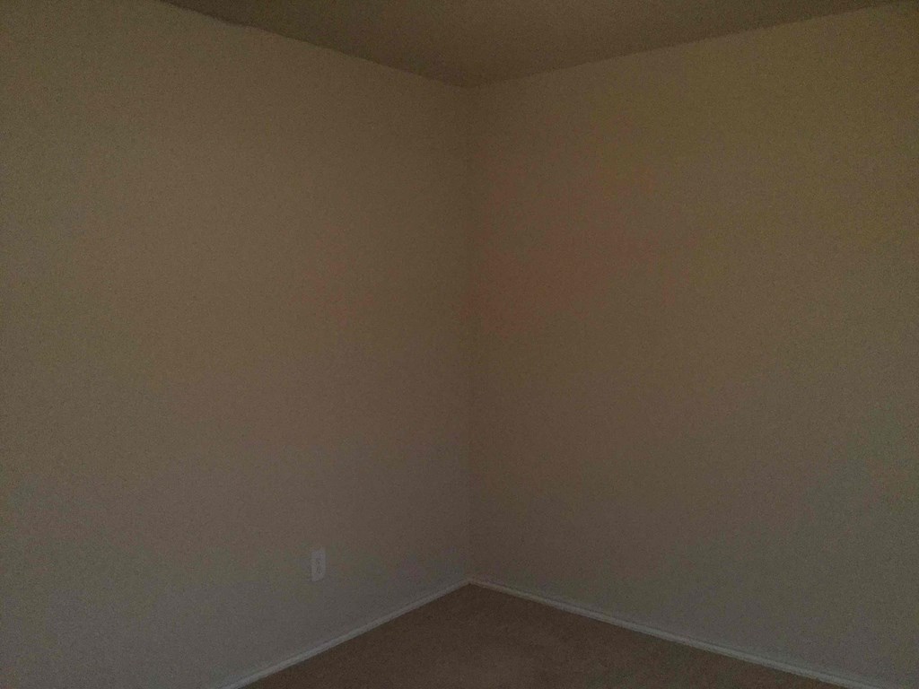 an empty room with beige walls and a brown floor