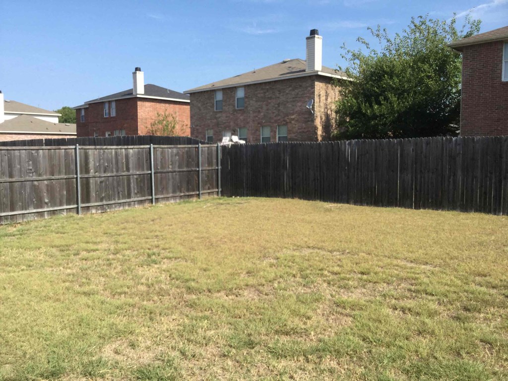 a backyard with a fence and a house behind it