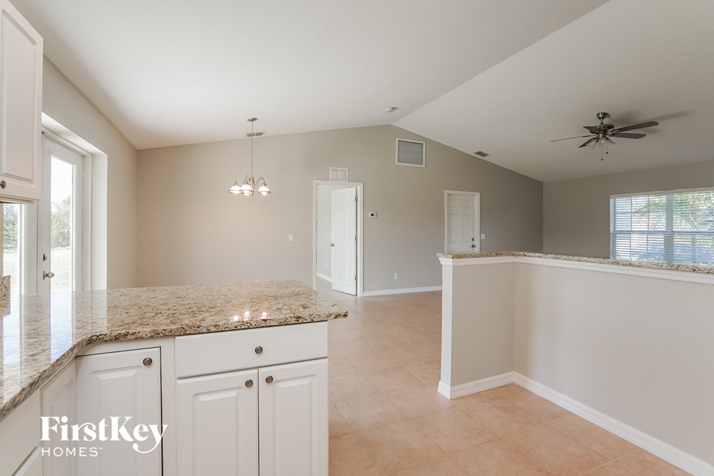an empty kitchen with white cabinets and a counter top