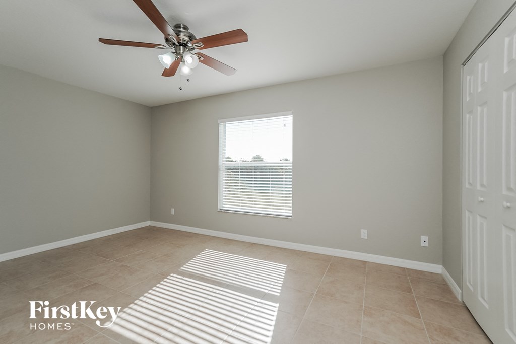 an empty room with a ceiling fan and a window