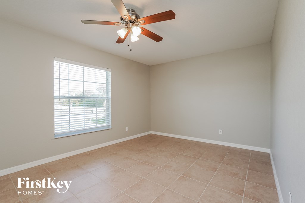 an empty room with a ceiling fan and a window